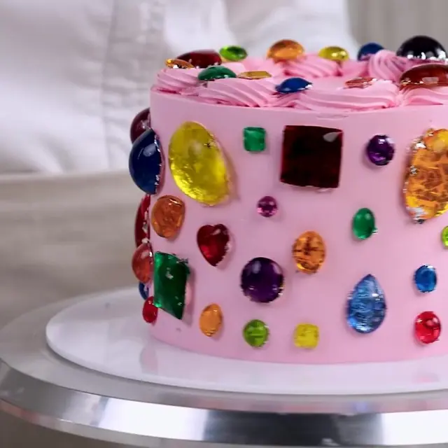 Pink cake covered edge to edge with edible gems of every color