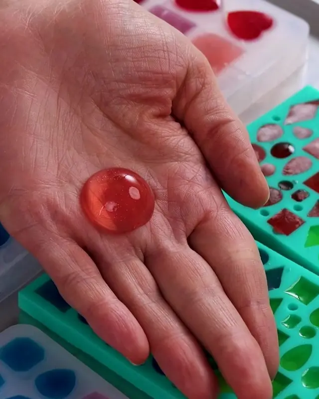 A round red edible gem resting on an open palm