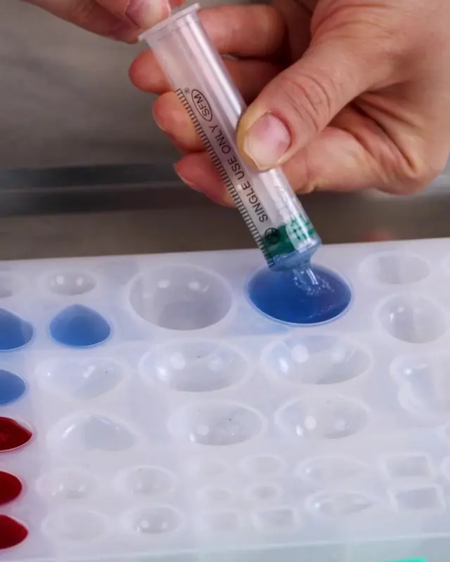 Filling a clear gem mold with blue gelatin from a syringe