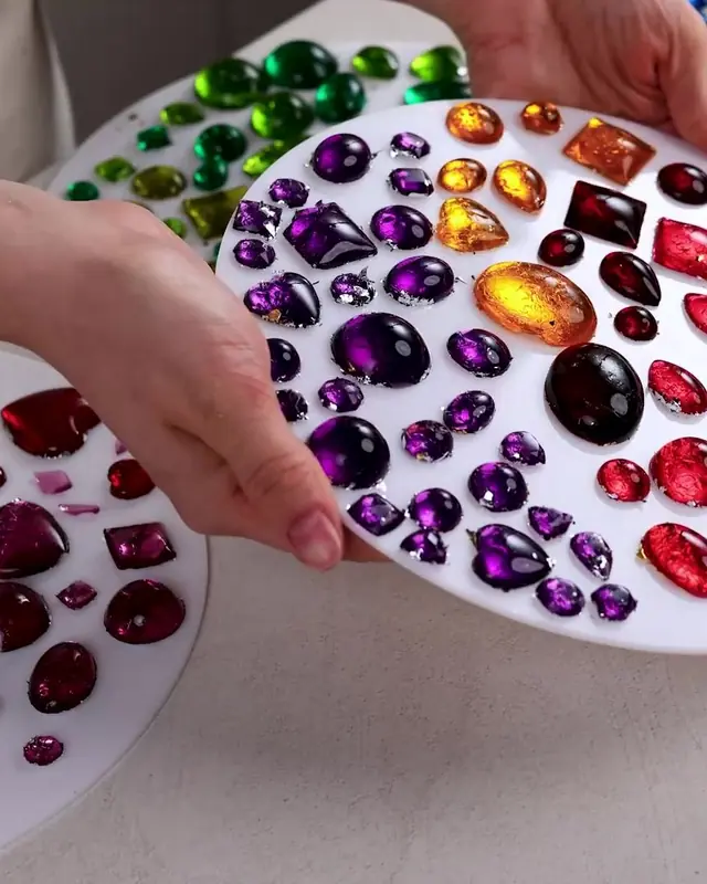 Hand holding a plate covered in purple, red, and gold edible gems