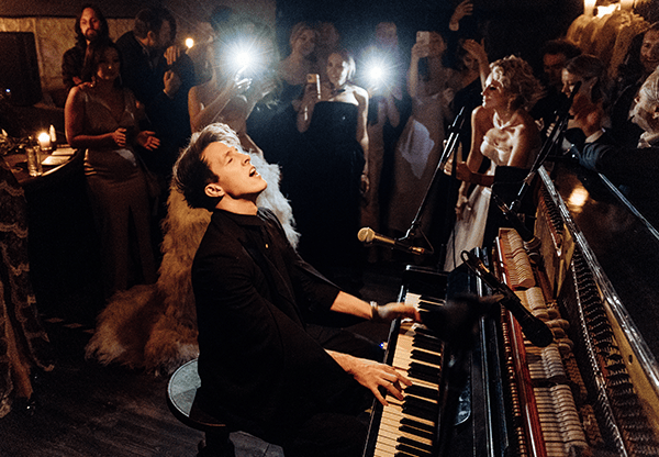 Stephen Ridley at the piano surrounded by an engaged, smiling audience